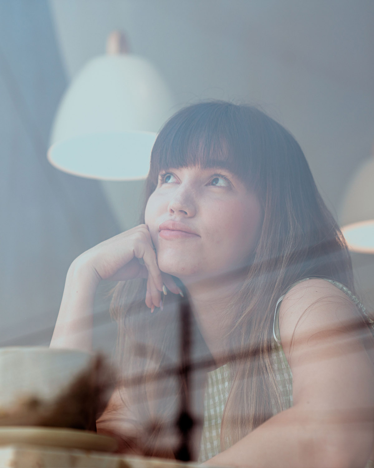 A woman reflecting thoughtfully, resting her chin on her hand and looking upward with a calm expression