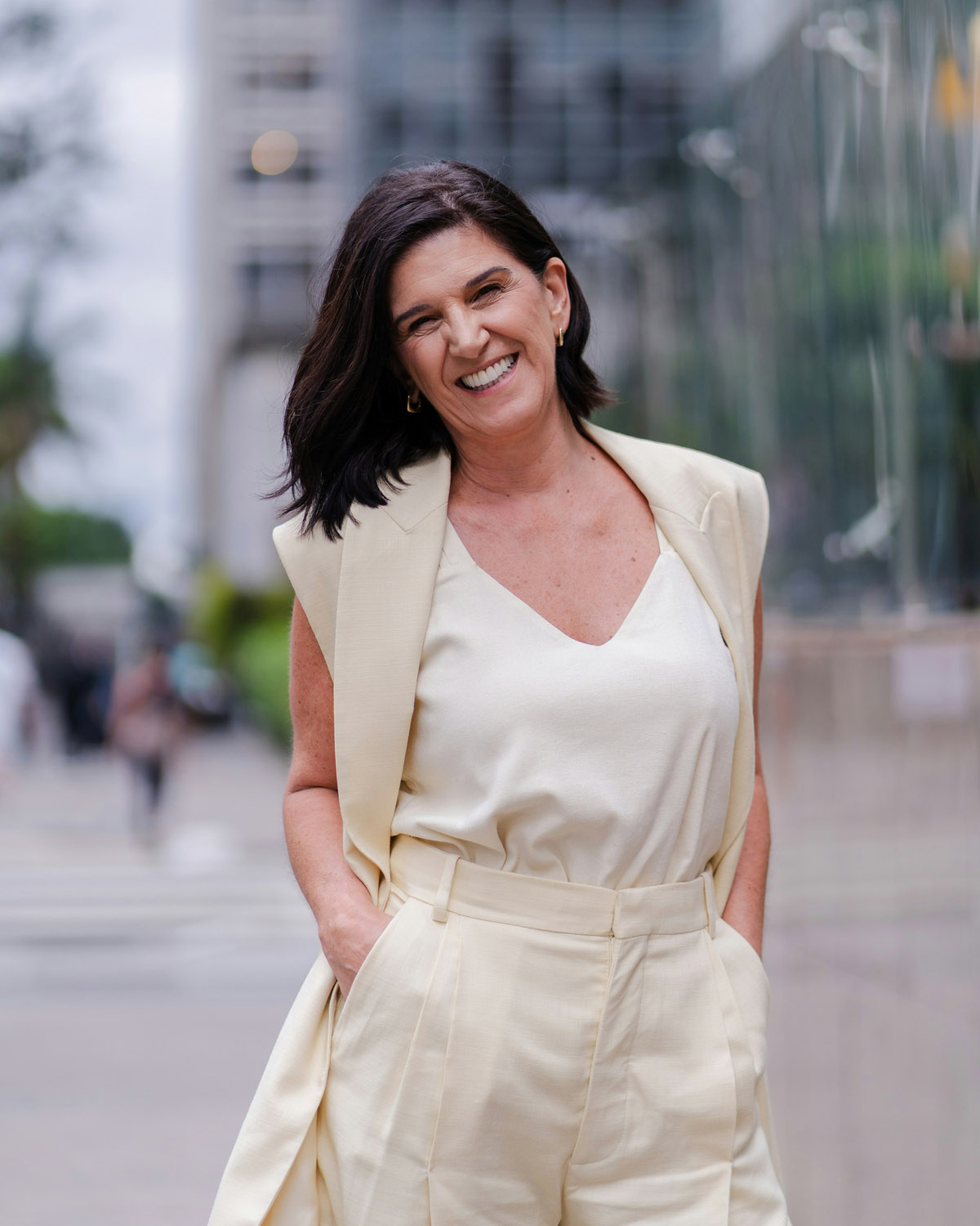 A smiling woman in professional attire outdoors in an urban setting