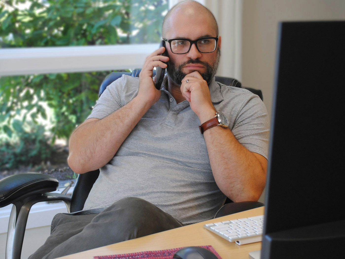 A man seated at a desk on a phone call, representing the stress and fatigue that often accompany stubborn weight